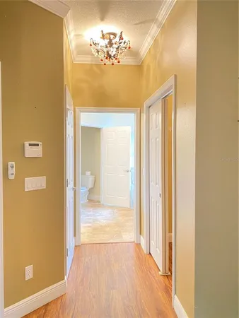 a view of a hallway with wooden floor and a bathroom