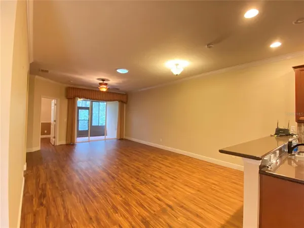 a view of empty room with wooden floor and fan