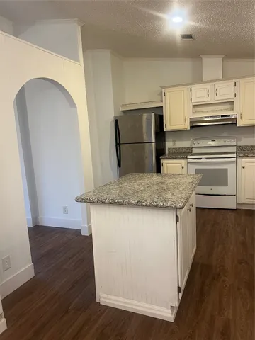 a kitchen with kitchen island granite countertop a sink stove and refrigerator