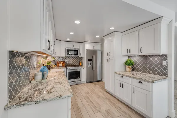 a kitchen with stainless steel appliances kitchen island granite countertop a refrigerator sink and cabinets