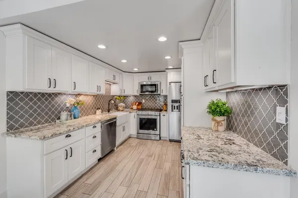 a kitchen with stainless steel appliances kitchen island granite countertop a stove a sink and a refrigerator