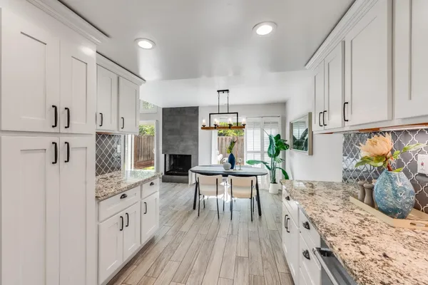 a kitchen with stainless steel appliances kitchen island granite countertop a refrigerator a stove a sink dishwasher and white cabinets with wooden floor