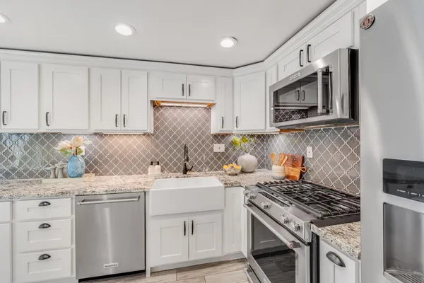 a kitchen with stainless steel appliances granite countertop a stove a sink and a microwave