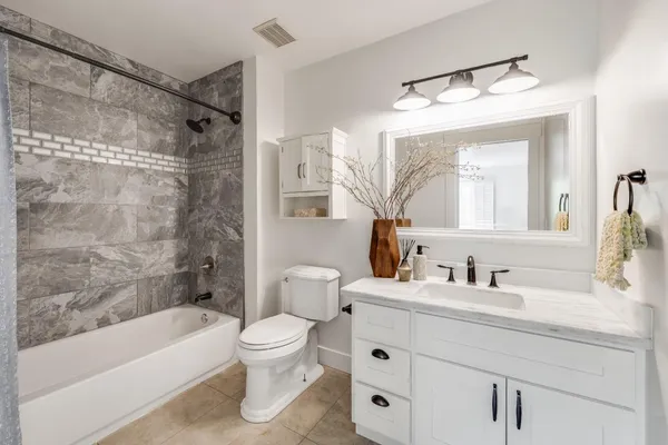a bathroom with a bathtub shower sink vanity and toilet