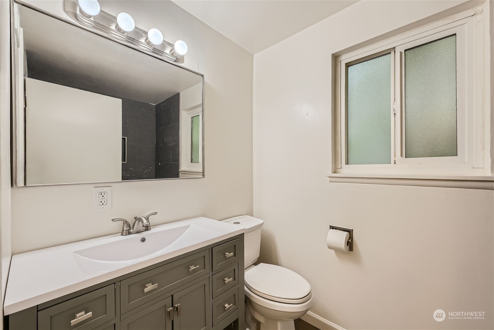 8536 Nesbit Avenue North, Unit A Seattle, WA 98103 - Photo 18 of 32 a bathroom with a toilet a sink and mirror