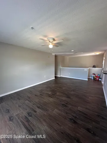a view of a room with wooden floor and ceiling fan