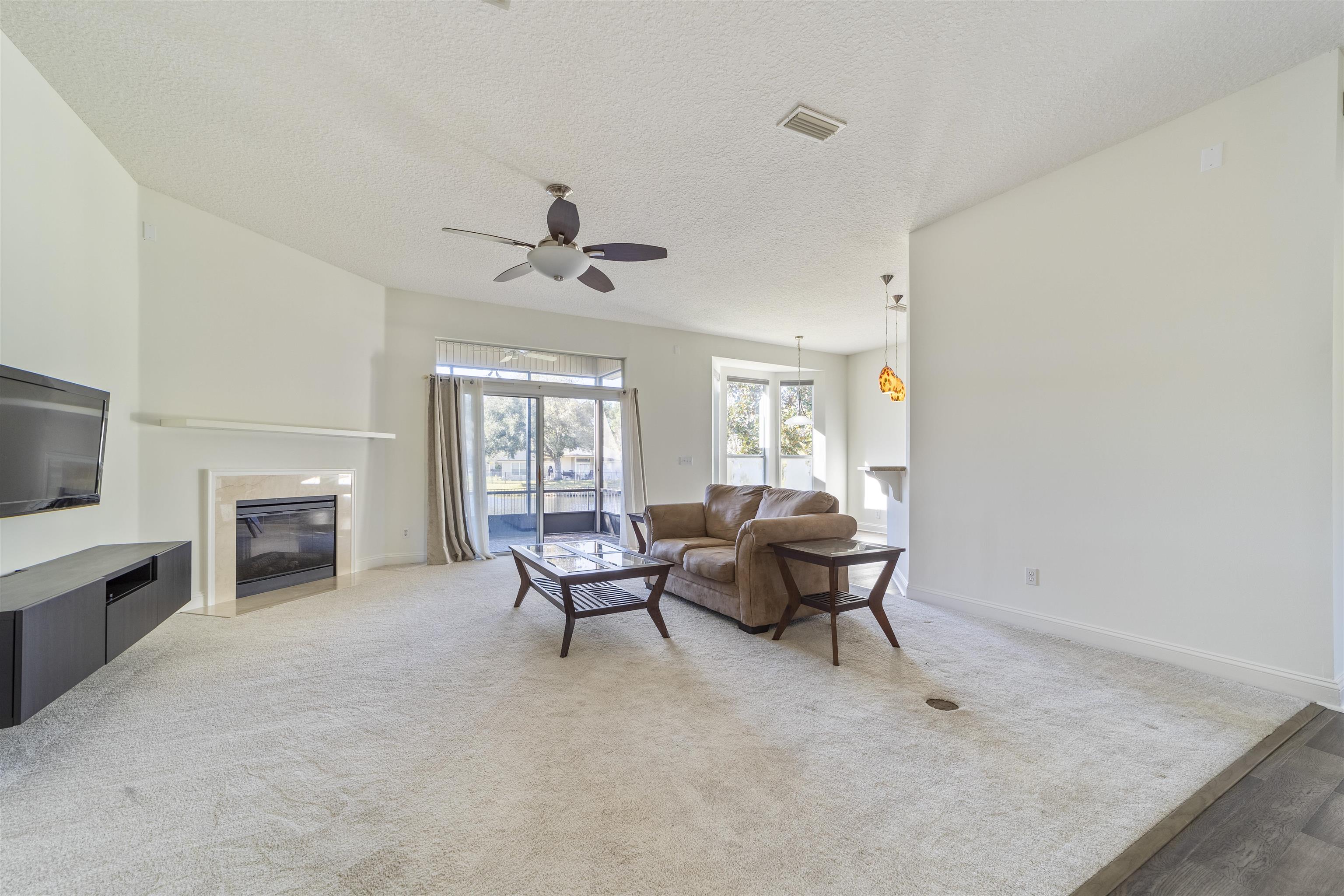 145 Whisper Ridge Drive St. Augustine, FL 32092 - Photo 11 of 32 a living room with furniture a fireplace and a flat screen tv