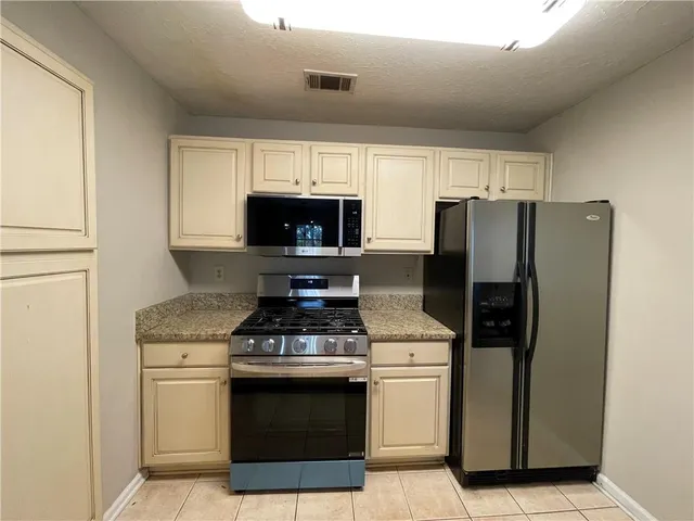 a kitchen with granite countertop a refrigerator and microwave
