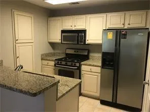 a kitchen with granite countertop a sink stove and refrigerator