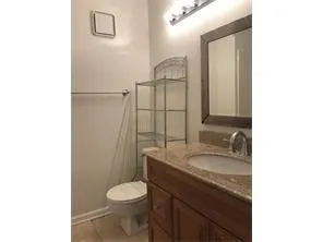 a bathroom with a granite countertop toilet sink and mirror