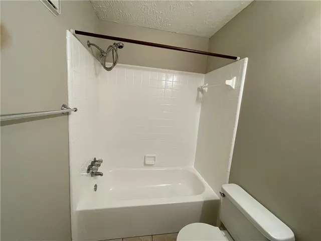 a bathroom with a granite countertop sink toilet a mirror a bathtub and shower