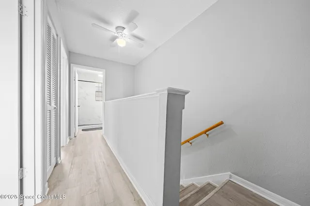 a view of a hallway with closet and a ceiling fan