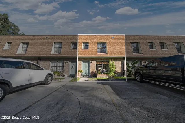 a view of a house with potted plants and a large tree