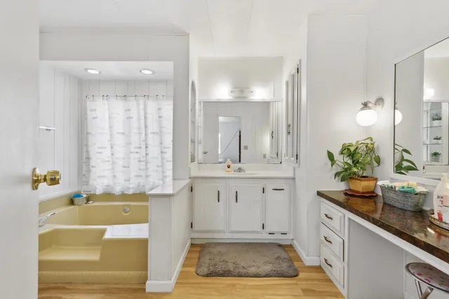 a spacious bathroom with a granite countertop tub a sink and a large mirror