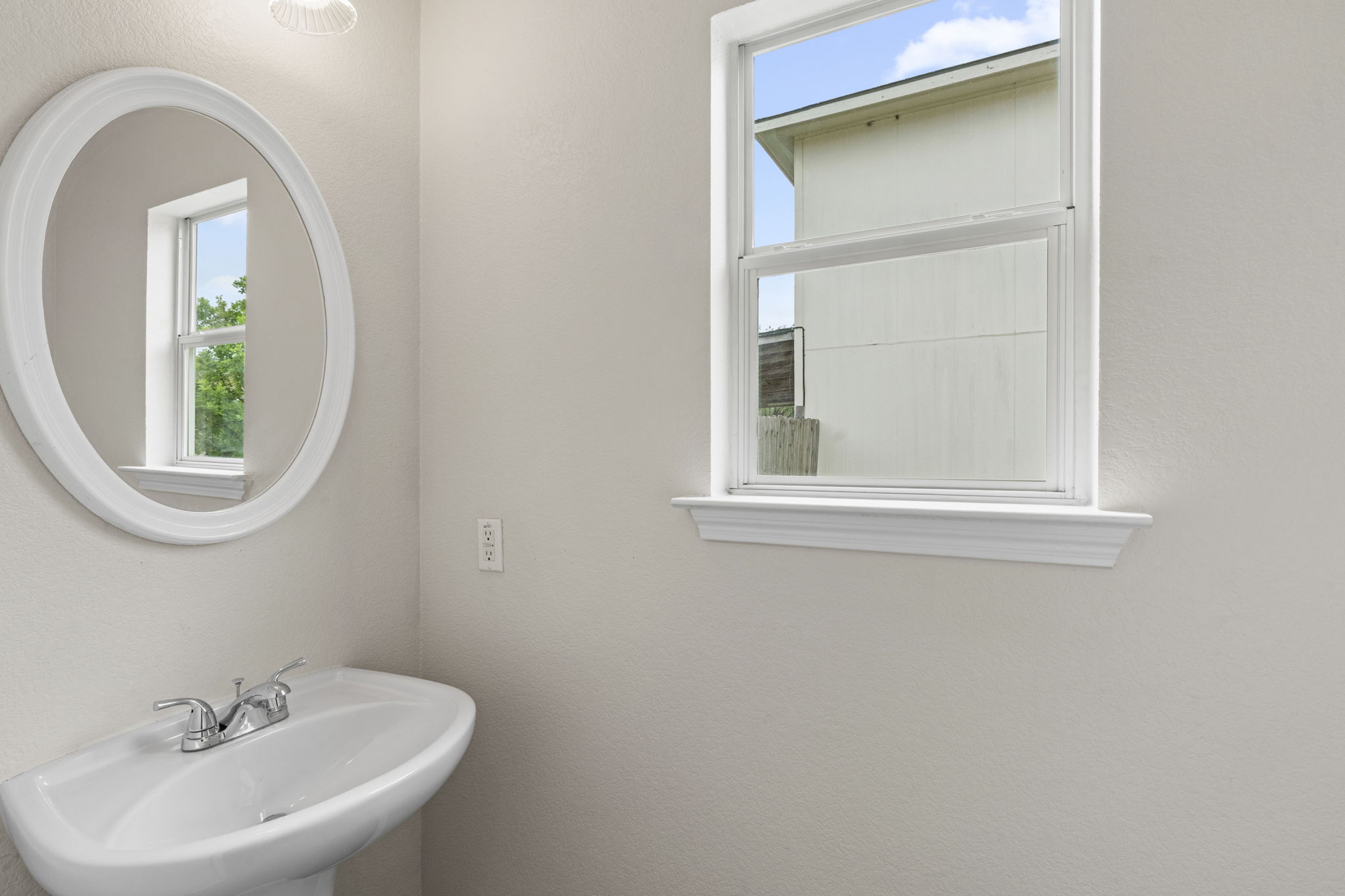 208 Dandelion Loop Kyle, TX 78640 - Photo 19 of 39 Half Bathroom on main level featuring a pedestal sink, a chrome faucet, and an oval mirror with a white frame