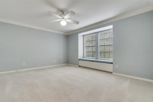 an empty room with chandelier fan and windows