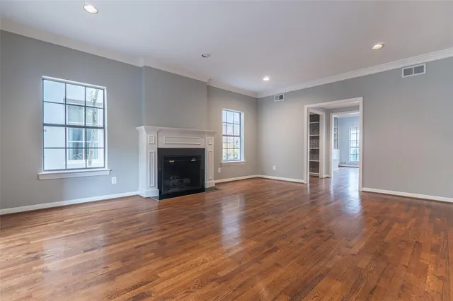 an empty room with wooden floor fireplace and windows