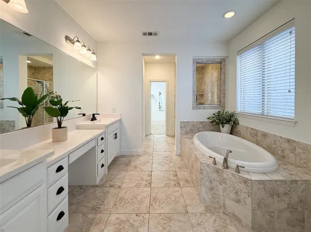 a spacious bathroom with a double vanity sink a large mirror and a bathtub