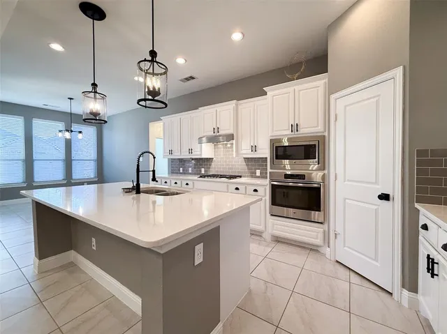 a kitchen with a sink a stove top oven and cabinets