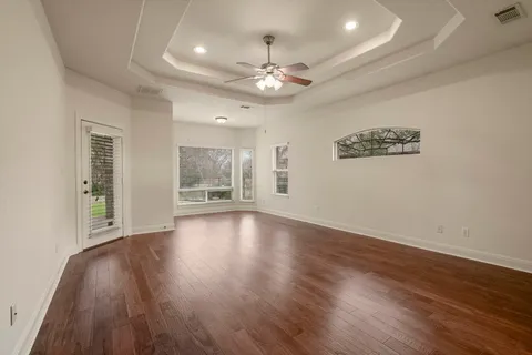 an empty room with wooden floor chandelier and windows