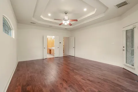 a view of an empty room with wooden floor and a ceiling fan