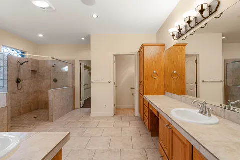 a spacious bathroom with a double vanity sink mirror and shower