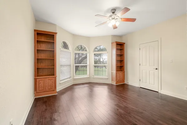 a view of an empty room with a window and wooden floor