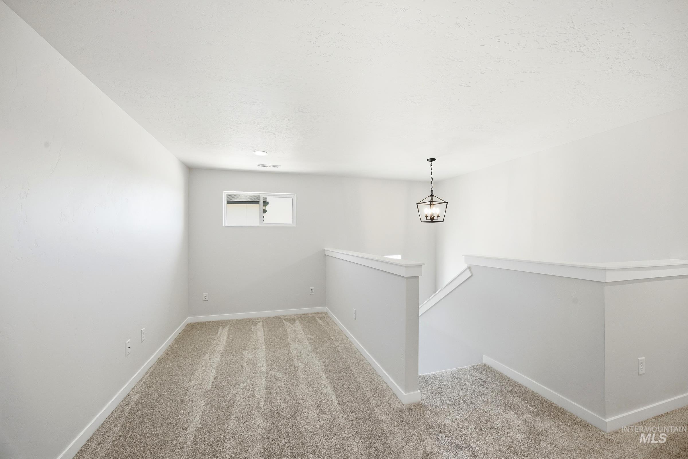 12841 Decatur Street Nampa, ID 83651 - Photo 21 of 30 Carpeted upper-level landing featuring a contemporary chandelier, white walls, white trim, and a window with a barn door style shutter