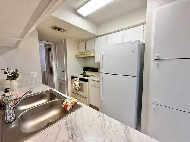 a kitchen with granite countertop a refrigerator and a sink