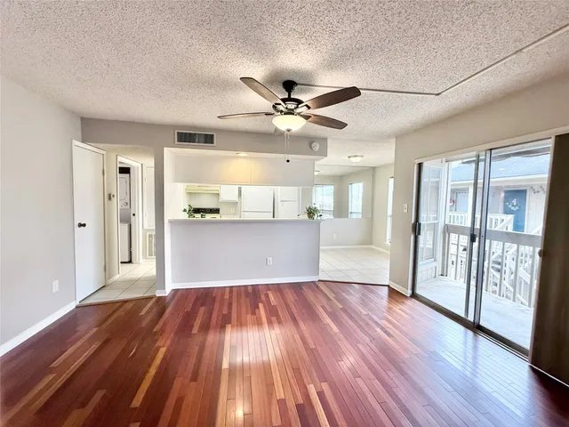 a view of a big room with wooden floor and a kitchen