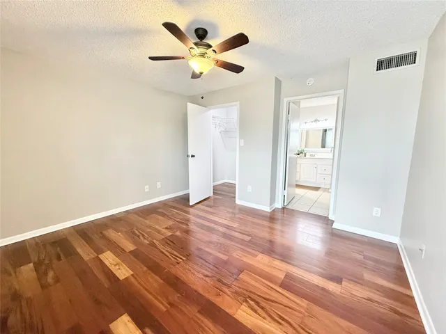 an empty room with wooden floor and a ceiling fan