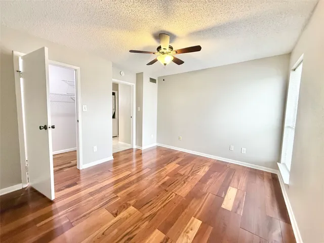 an empty room with wooden floor and ceiling fan