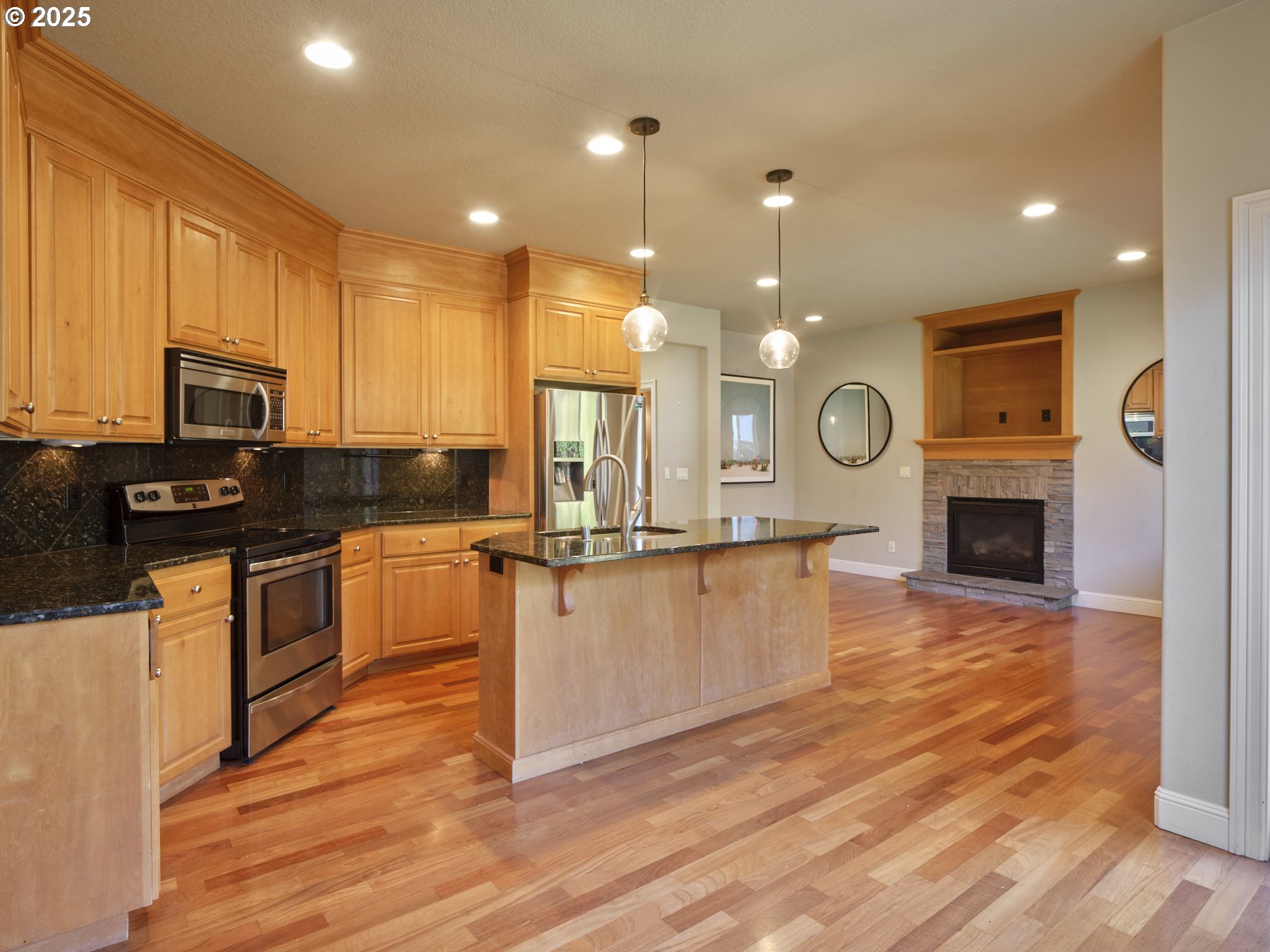 10410 Southeast French Road Vancouver, WA 98664 - Photo 12 of 43 a large kitchen with kitchen island granite countertop a stove a sink a refrigerator and white cabinets with wooden floor