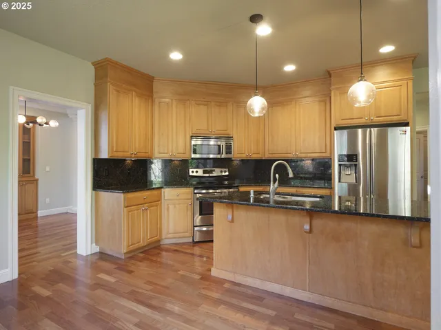 a kitchen with stainless steel appliances granite countertop a sink a stove and a refrigerator