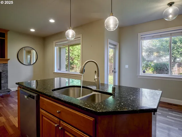 a kitchen with granite countertop a sink a window and wooden floor