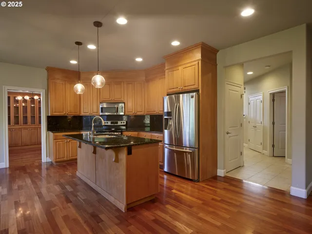 a kitchen with stainless steel appliances kitchen island granite countertop a refrigerator and a stove