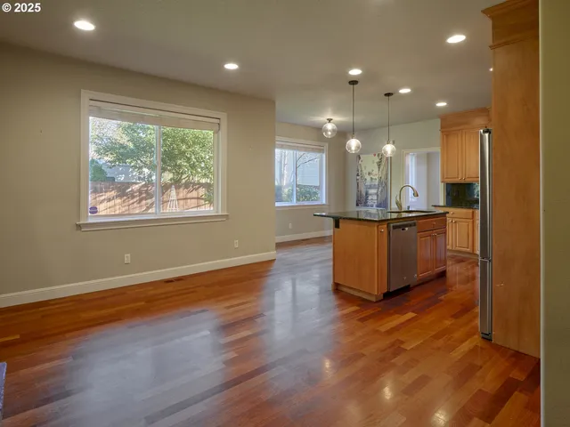 an open kitchen with kitchen island granite countertop wooden floor and a sink
