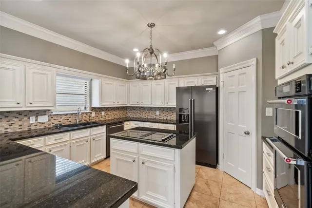 a kitchen with stainless steel appliances granite countertop a refrigerator a sink dishwasher a stove and white cabinets