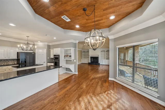 a large living room with kitchen island stainless steel appliances furniture a large window and a chandelier