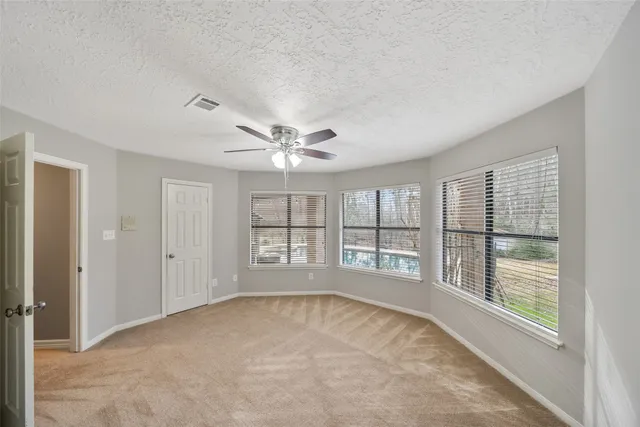 an empty room with windows and chandelier fan