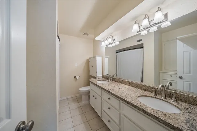 a spacious bathroom with a granite countertop double vanity sink a mirror and a shower