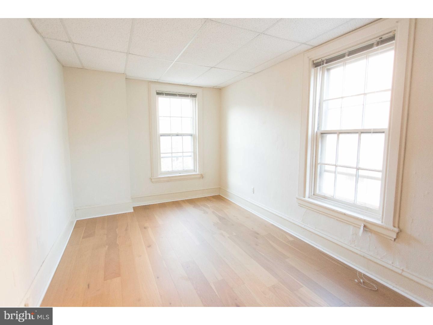 901 Clinton Street, Unit 1 Philadelphia, PA 19107 - Photo 17 of 23 an empty room with wooden floor and windows