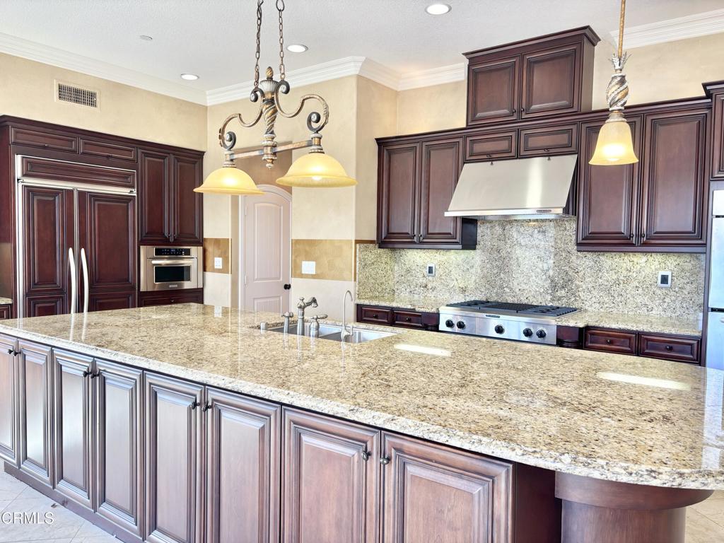 1702 Aleutian Way Oxnard, CA 93035 - Photo 29 of 73 a kitchen with granite countertop a stove a sink and a wooden cabinets