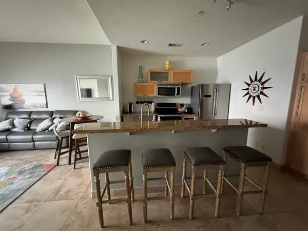 a living room with furniture a flat screen tv and a refrigerator