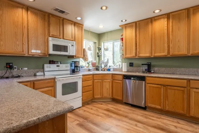 a kitchen with stainless steel appliances granite countertop a stove a sink dishwasher and a microwave oven with white cabinets