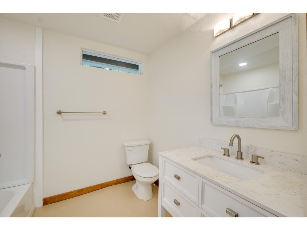 106 South Ave A, Unit E Elgin, TX 78621 - Photo 25 of 30 a bathroom with a granite countertop sink a toilet and a mirror