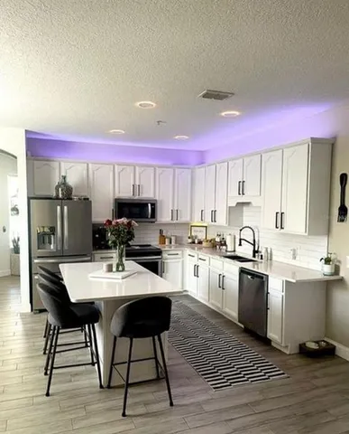 a kitchen with a stove a sink dishwasher and a refrigerator with wooden floor