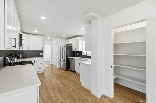 a kitchen with a refrigerator a sink and white cabinets