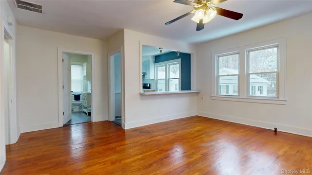 a view of empty room with wooden floor and fan