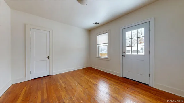 a view of empty room with window and wooden floor